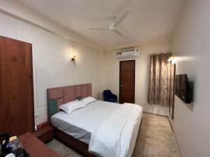 a bedroom with a white bed and a tv at Kasa Comfort Inn in Indore