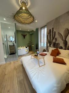 1 Schlafzimmer mit einem großen weißen Bett und einem Badezimmer in der Unterkunft Suite avec Jacuzzi, 15 min de Disneyland Paris - Le Nid d'Eliyah in Nanteuil-lès-Meaux