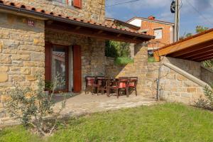 a stone house with a table and chairs on a patio at Istrian House La Bora in Koper