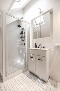 a white bathroom with a shower and a sink at The Rest Family Cottage with Resort Style Pool in Noosa Heads