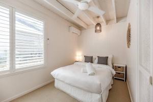 a white bedroom with a bed and a window at The Rest Family Cottage with Resort Style Pool in Noosa Heads +42 photos