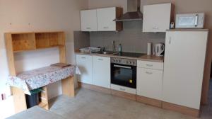 cocina con armarios blancos, fregadero y fogones en Pension Sommer, en Locktow