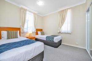 Un dormitorio con 2 camas y una silla. en C Mandurah Apartment Resort, en Mandurah
