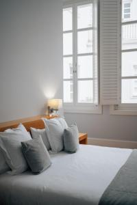 una camera da letto con un letto con cuscini bianchi e una finestra di Hotel Boutique Palacio Corredera a Jerez de la Frontera