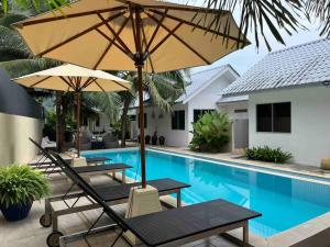 two tables and an umbrella next to a swimming pool at Tropical Private Pool Villa 500m to the beach in Pantai Cenang
