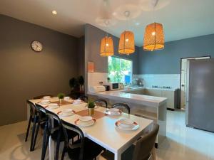 a dining room with a table and a kitchen at The Fint Hus Villa Langkawi in Pantai Cenang