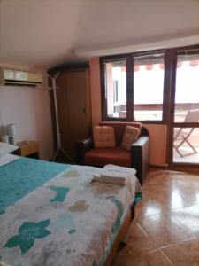 a bedroom with a bed and a chair and windows at Guesthouse Olimp in Sozopol