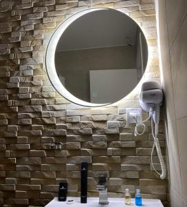 a bathroom with a mirror on a brick wall at Apartmani Vila Ana in Gunjica