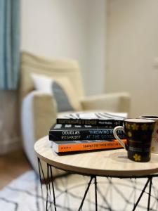 a stack of books on a table next to a coffee cup at La ruche Arrageoise - Parking gratuit - Cozy - Grand lit - Long séjour in Arras