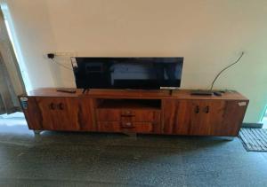 a wooden entertainment center with a flat screen tv on it at Vrundhavan Agro Tourism 