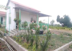 a house with a garden in front of it at Vrundhavan Agro Tourism 