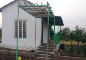 a small white house with a green roof at Vrundhavan Agro Tourism 