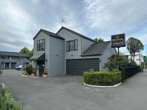 a white house with a garage and a sign at Samhil Motor Lodge in Christchurch