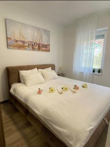 a white bed with some flowers on top of it at Apartmani Vila Ana in Gunjica