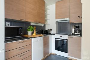una cocina con electrodomésticos blancos y armarios de madera en Holiday in Lapland - Alppilevi 1 B1, en Kittilä