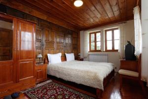 Schlafzimmer mit einem Bett und holzgetäfelten Wänden in der Unterkunft Yovina House Zheravna in Scherawna