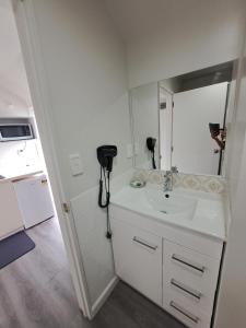 a white bathroom with a sink and a mirror at Samhil Motor Lodge in Christchurch