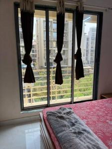 a bedroom with a bed and a large window at La Residence in Navi Mumbai