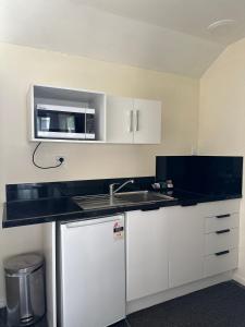 a kitchen with a sink and a microwave at Samhil Motor Lodge in Christchurch