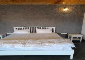a white bed with two pillows and two tables at Vrundhavan Agro Tourism 