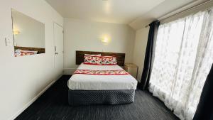 1 dormitorio con cama y ventana grande en Samhil Motor Lodge en Christchurch