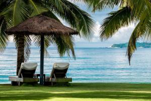 三亞的住宿－三亚安隅酒店，海滩上一把稻草伞下的两把椅子