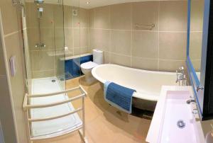 a bathroom with a tub and a toilet and a sink at The Mill House in Santon