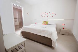 um quarto branco com uma cama com uma mulher sentada nele em Sunseverino Rooms em Montecorice
