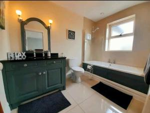 a bathroom with a green cabinet and a tub and a toilet at Limestone Lodge Apartment in Doolin