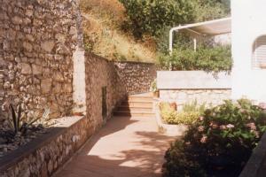 un muro di pietra con una scala accanto a un edificio di Residenza Santa Maria a Capri