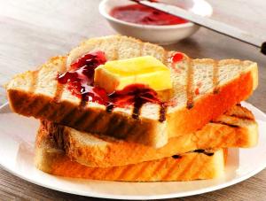 een bord met twee stukken toast met boter en jam bij FabHotel Royal King I in Surat