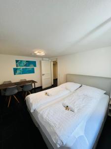 un grande letto bianco in una stanza con scrivania di Souterrain 2 Zimmer Wohnung Freiburg Seepark a Friburgo in Brisgovia