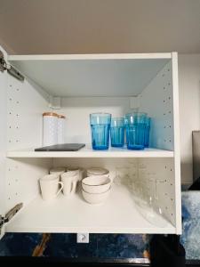 a white shelf with blue bowls and cups on it at Souterrain 2 Zimmer Wohnung Freiburg Seepark in Freiburg im Breisgau