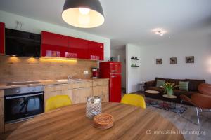 une cuisine et un salon avec une table et des armoires rouges dans l'établissement Lago Rosso, à Langenargen