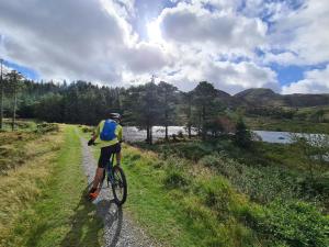 un hombre montando una bicicleta por un camino de tierra en Delightful Camping Pod in Snowdonia, North Wales., en Derwen