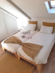 2 camas con sábanas blancas y almohadas en una habitación en River & Beach Apartment near Lisbon, en Trafaria