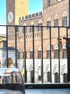 un gran edificio de ladrillo con un reloj. en The Balcony Suite - affaccio su Piazza del Campo, en Siena