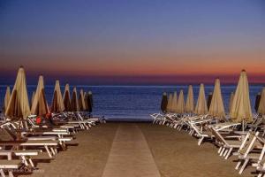 een rij stoelen en parasols op een strand bij Color Alexandra Plaza Family Hotel in Riccione