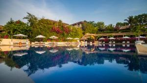 een groot zwembad met parasols, stoelen en bomen bij Victoria Phan Thiet Beach Resort & Spa in Mũi Né