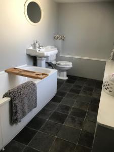 La salle de bains est pourvue d'un lavabo, d'une baignoire et de toilettes. dans l'établissement The Malt Scoop Inn, à Merton