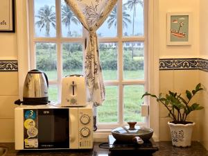 貝瑙利姆的住宿－CHALET SAFFRON GOA Breakfast Included，微波炉,坐在窗前的柜台上