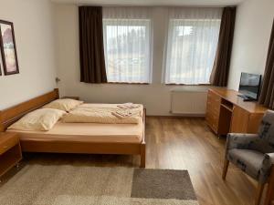 a bedroom with a bed and a desk and a chair at Penzión Uhliská in Nižná