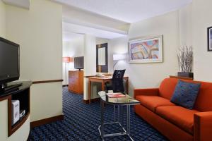 a hotel room with a couch and a tv at Fairfield Inn & Suites Charlotte Arrowood in Charlotte