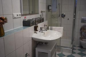 a white bathroom with a sink and a shower at Ferienwohnung zum Lausbub in Eckersdorf