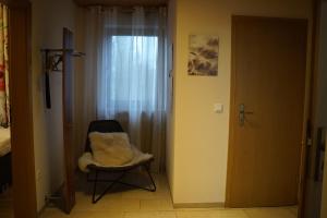 a room with a chair and a window and a door at Ferienwohnung zum Lausbub in Eckersdorf