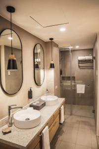 two sinks in a bathroom with two mirrors and a shower at Mandarin Nest Boracay in Boracay