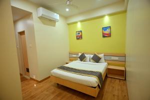 een slaapkamer met een bed in een kamer met gele muren bij Hotel City Centre Latur in Lātūr