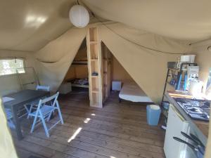 una habitación con una tienda de campaña con una mesa y una escalera en Camping de la Bucherie, en Saint-Saud-Lacoussière
