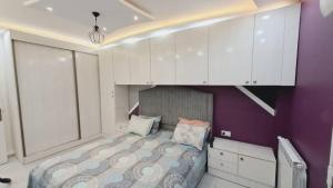 um quarto com uma cama com paredes roxas e armários brancos em Appartement pour vacances em Boumerdès