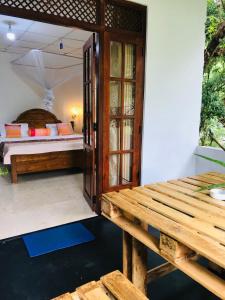 a room with a bed and a wooden table at Sandaro Rest Inn in Ella